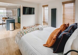 A hotel room with a bed, a TV, a desk, and a view of the outdoors.
