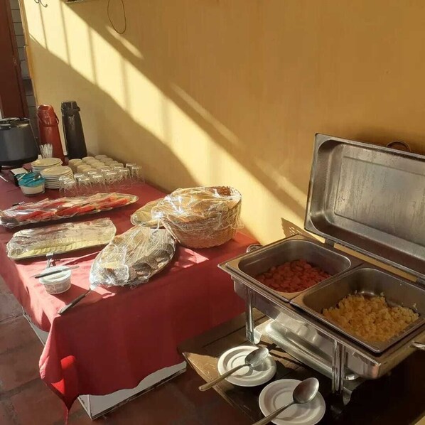 A buffet setup with various food items and utensils on a red tablecloth. - OASIS INN, ON THE BEACH OF RIO A SPECTACLE ON MOSQUEIRO ISLAND. (Mosqueiro)
