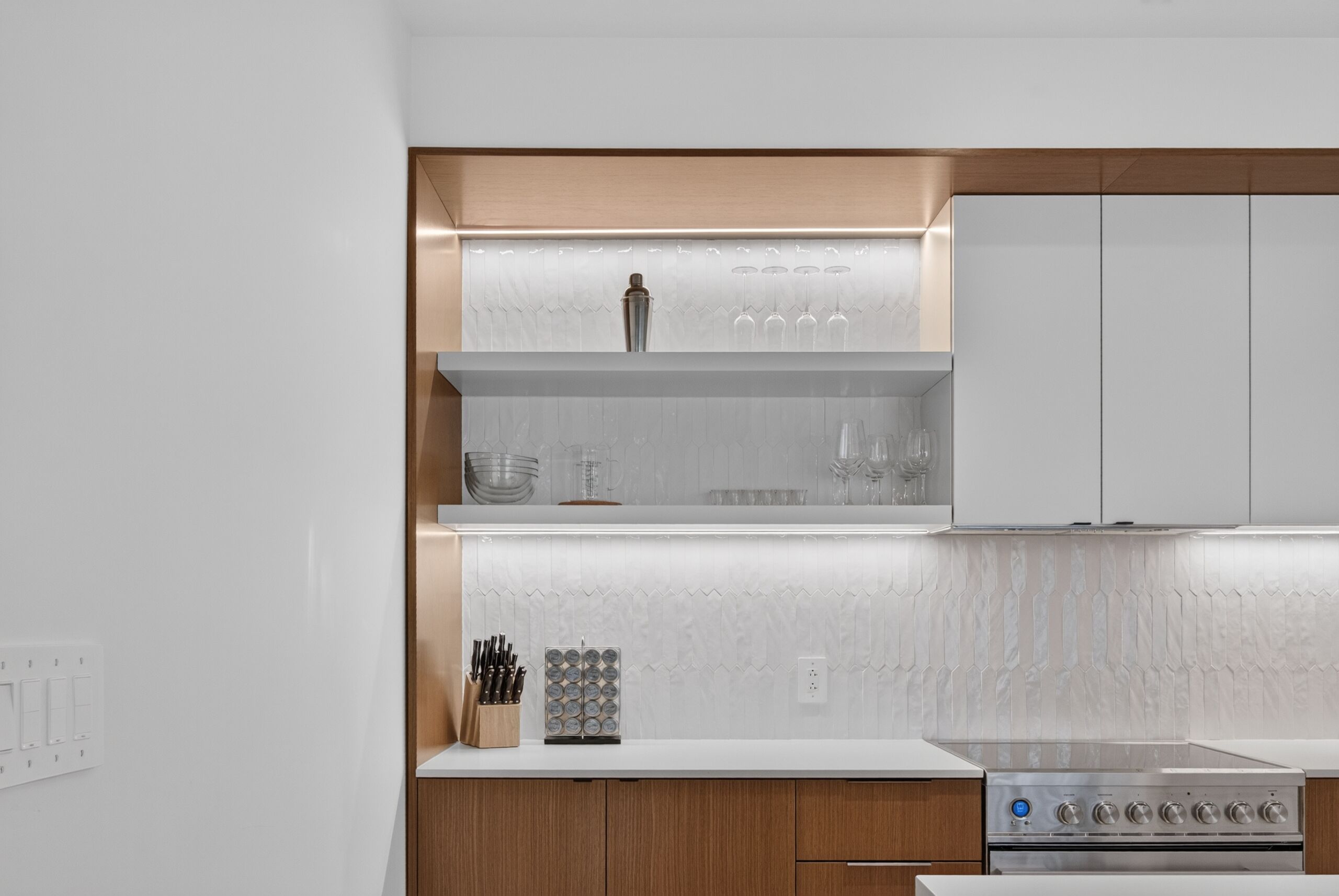 Una cocina moderna con armarios blancos, estufa de acero inoxidable y un bloque para cuchillos.