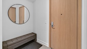 A hallway with a wooden door, a round mirror, and a bench.