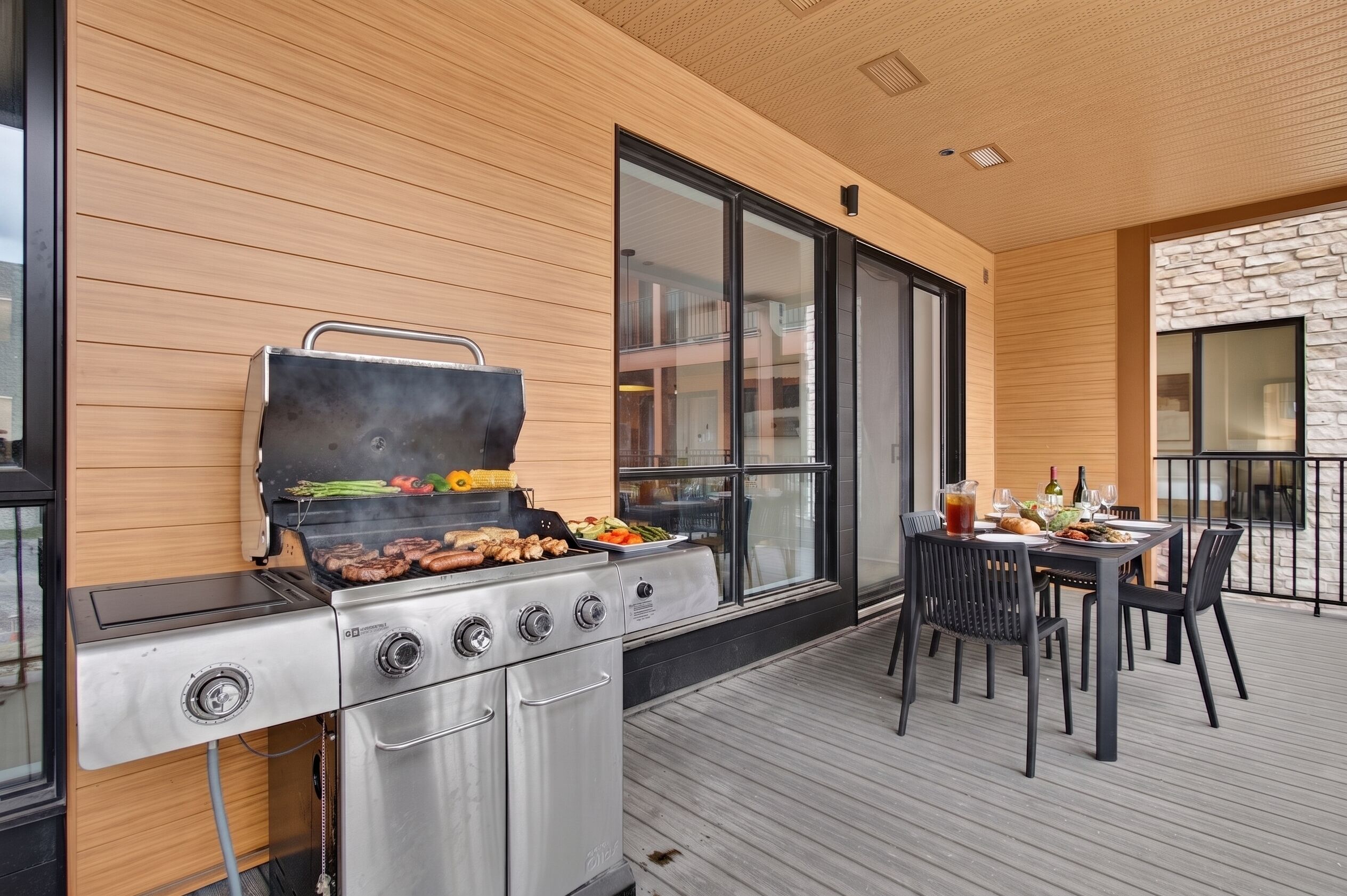 Un patio al aire libre con una parrilla, una mesa de comedor y sillas.