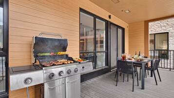 Un patio al aire libre con una parrilla, una mesa de comedor y sillas.