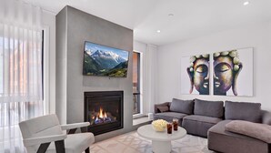 A modern living room with a fireplace, a sofa, a coffee table, and artwork on the walls.