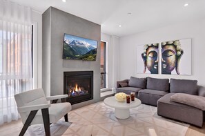 Un salon moderne avec une cheminée, un canapé, une table basse et des œuvres d’art accrochées aux murs.