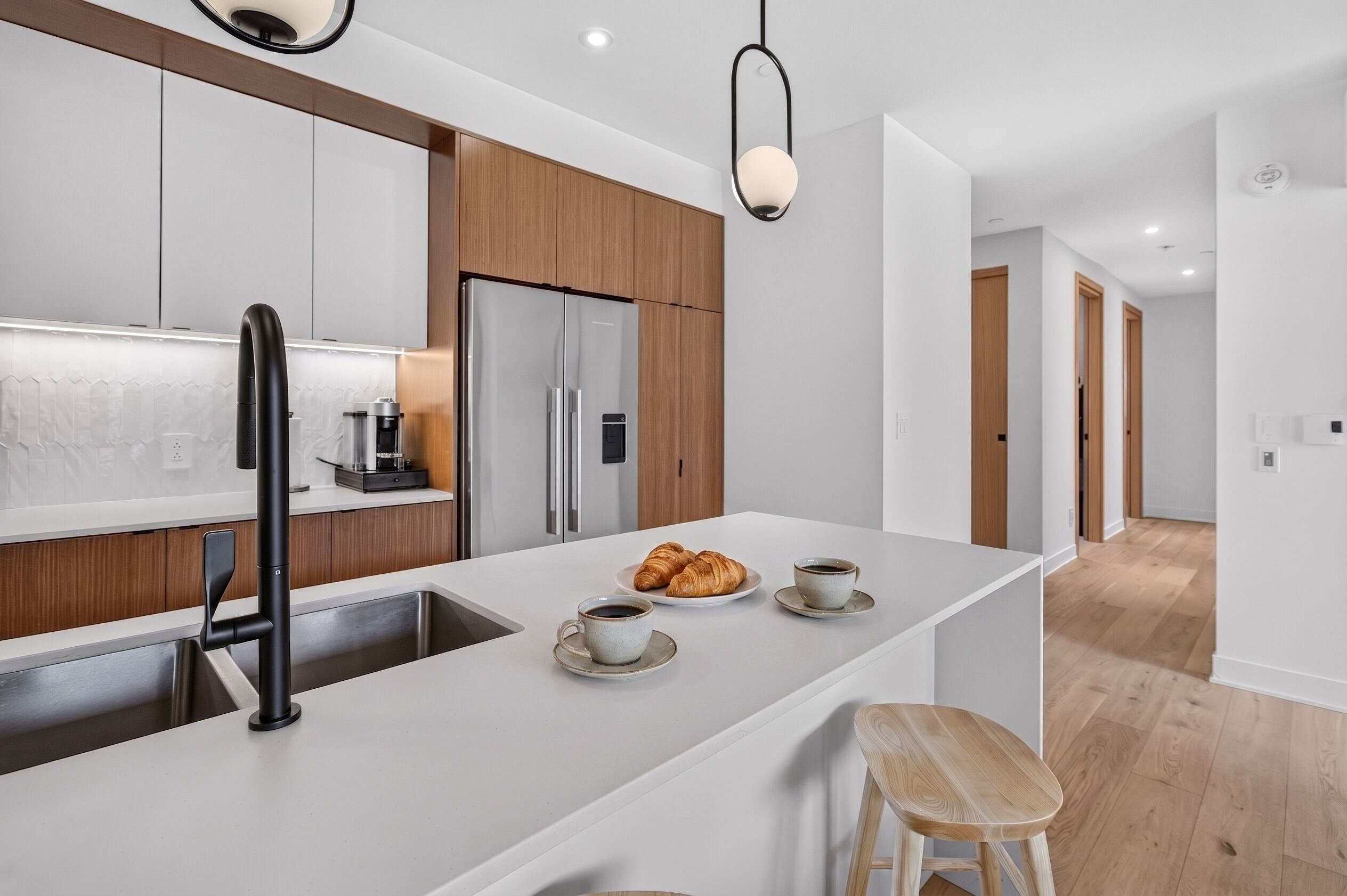 A modern kitchen with a central island, stainless steel appliances, and a wooden accent wall.