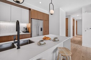 Une cuisine moderne dotée d’un îlot central, d’appareils électroménagers en acier inoxydable et d’un mur d’accent en bois.
