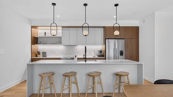 Una cucina moderna con isola centrale, sgabelli da bar e luci a sospensione.
