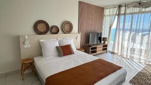 A bedroom with a large bed, a TV, and a view of the sea. - Horizon Caraibes (Le Gosier)