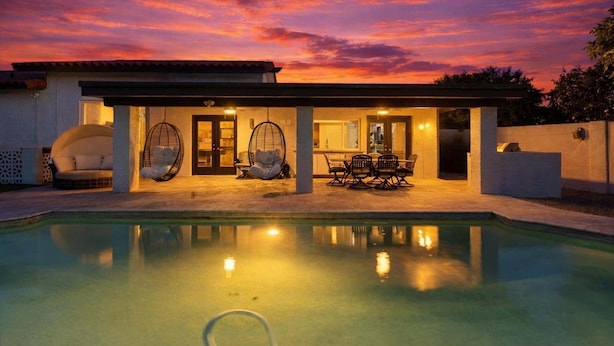 A modern house with a swimming pool, outdoor seating, and a sunset view.
