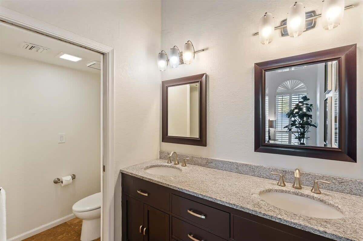 Une salle de bain avec un double lavabo, un miroir et un luminaire.