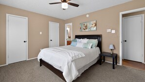 A bedroom with a bed, a nightstand, a ceiling fan, and two doors. -  3BR Home Near Fort Cavazos Game Room Military Friendly (Killeen)