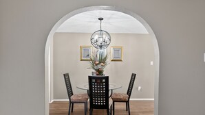 A dining area with a round glass table, black chairs, a central decorative piece, and a chandelier. -  3BR Home Near Fort Cavazos Game Room Military Friendly (Killeen)