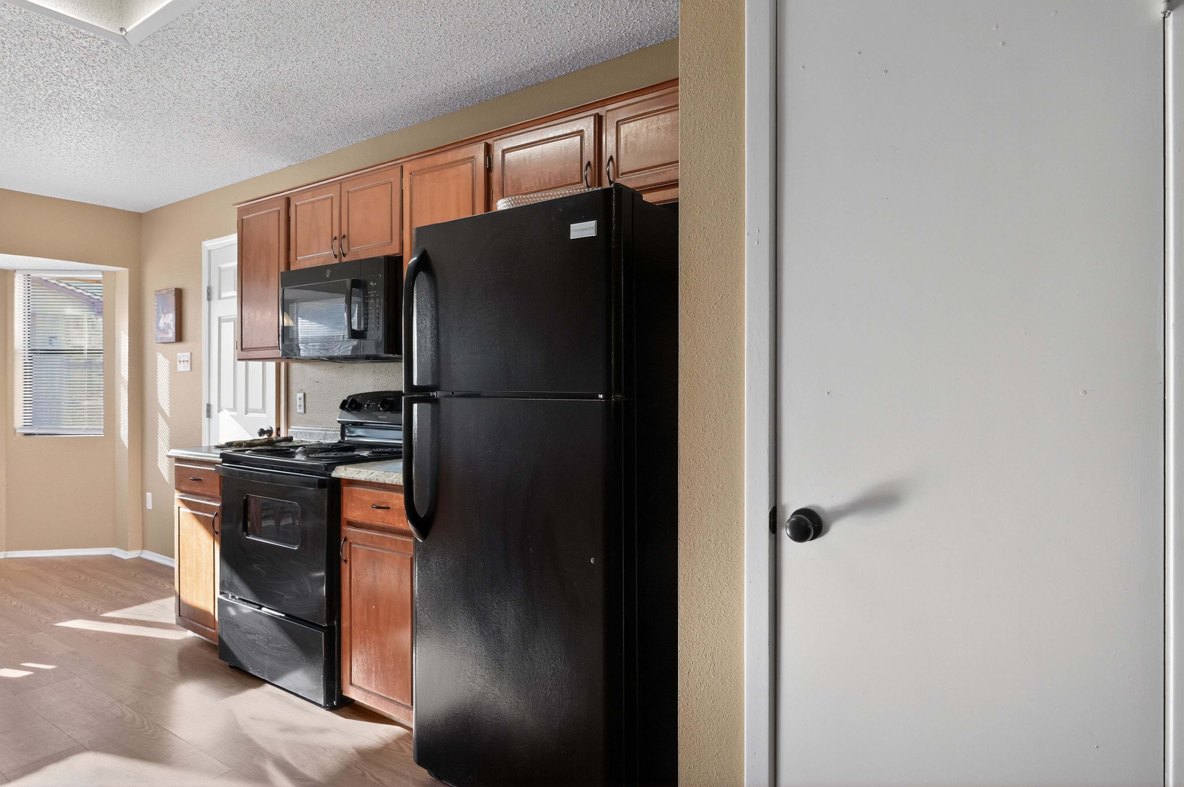 Una cocina con armarios de madera, un refrigerador negro, una estufa y un microondas.