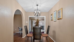 A dining area with a round table, four chairs, a chandelier, and framed pictures on the wall. -  3BR Home Near Fort Cavazos Game Room Military Friendly (Killeen)