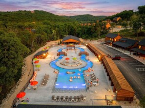 Un complexe hôtelier doté d’une grande piscine, d’un espace extérieur aménagé et de cabanes.
