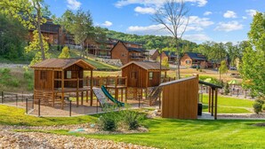 Un chalet avec des cabanes en bois, une aire de jeux et un petit bâtiment.