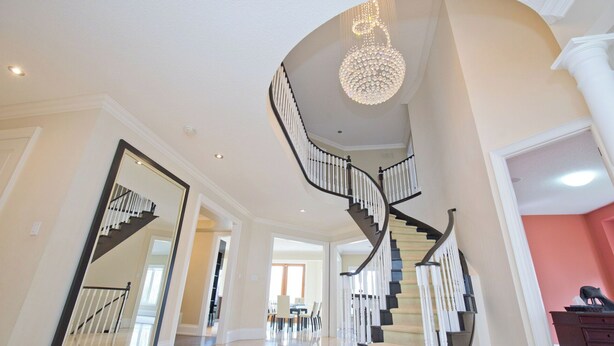 A grand staircase with a chandelier, leading to a dining area with chairs and a table. - 6000 sqft Executive 6 BR Home in Prestigious Area (Mississauga)