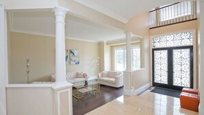 A spacious living room with a high ceiling, white columns, and a large window. There are two white sofas and a glass coffee table. - 6000 sqft Executive 6 BR Home in Prestigious Area (Mississauga)