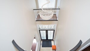 A staircase with a chandelier, a door with decorative glass panels, and a small orange bench. - 6000 sqft Executive 6 BR Home in Prestigious Area (Mississauga)
