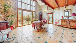 A spacious room with a stone wall, large windows, a wooden ceiling, and a tiled floor. - 2 bedroom awesome home in Saint Lyphard (Saint Lyphard)