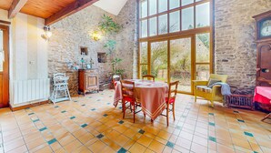 A dining area with a stone wall, wooden ceiling, and large windows. - 2 bedroom awesome home in Saint Lyphard (Saint Lyphard)