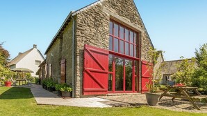 A stone building with a red door and windows, surrounded by a well-maintained garden. - 2 bedroom awesome home in Saint Lyphard (Saint Lyphard)