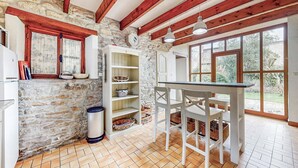 A rustic kitchen with stone walls, wooden beams, and a tiled floor. - 2 bedroom awesome home in Saint Lyphard (Saint Lyphard)