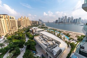 Un hôtel de grande hauteur doté d’une piscine sur le toit, offrant une vue sur la plage et, en arrière-plan, un panorama sur la ville.