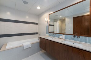 Une salle de bain moderne avec une grande baignoire, deux lavabos, des meubles en bois et un grand miroir.