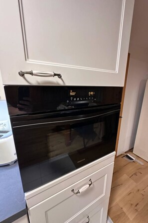 Een koelkast, een vaatwasser, kookgerei, borden en bestek