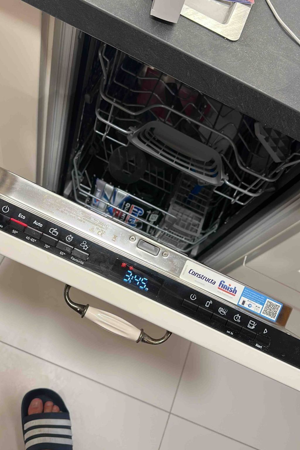 A dishwasher with a digital display and a QR code.