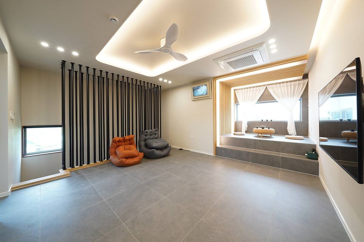 A modern living room with a ceiling fan, a TV, and a seating area with two chairs.