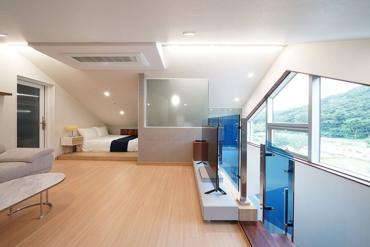 A modern bedroom with a bed, bedside table, and a view of a balcony.
