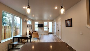 A modern kitchen with a large island, pendant lights, and a TV mounted on the wall.