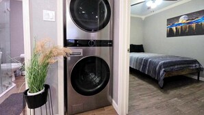 A compact room with a bed, a ceiling fan, and a wall-mounted washer and dryer unit. - FREE NIGHT! TV In Bedroom, Patio, Private  (Houston)