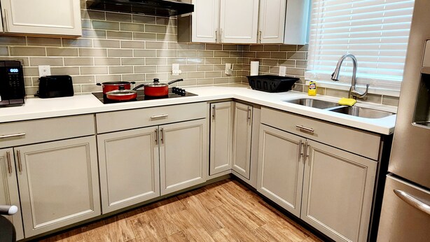 A kitchen with white cabinets, a black range hood, a window with blinds, and a stainless steel sink. - FREE NIGHT! TV In Bedroom, Patio, Private  (Houston)