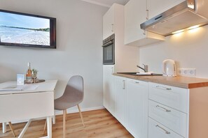 Una cucina moderna con mobili bianchi, un piano di lavoro in legno e un forno integrato.