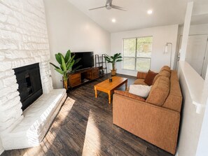A living room with a fireplace, a television, a sofa, and a coffee table. - Walkable Culdesac by Barton and Zilker (Austin)