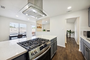 Una cucina moderna con piano cottura a gas, elettrodomestici in acciaio inossidabile e una grande finestra.
