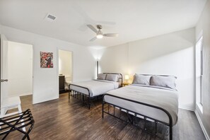 A room with two beds, a ceiling fan, a bedside table with a lamp, and a chair. - Walkable Culdesac by Barton and Zilker (Austin)