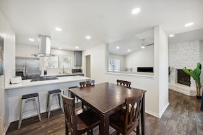 A modern kitchen with a central island, bar stools, and a dining table with chairs. - Walkable Culdesac by Barton and Zilker (Austin)