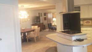 A modern kitchen with a built-in gas stove, a stainless steel range hood, and white cabinetry.