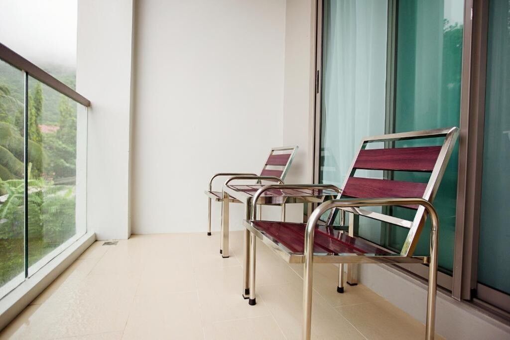 A balcony with two metal-framed chairs and a glass table.