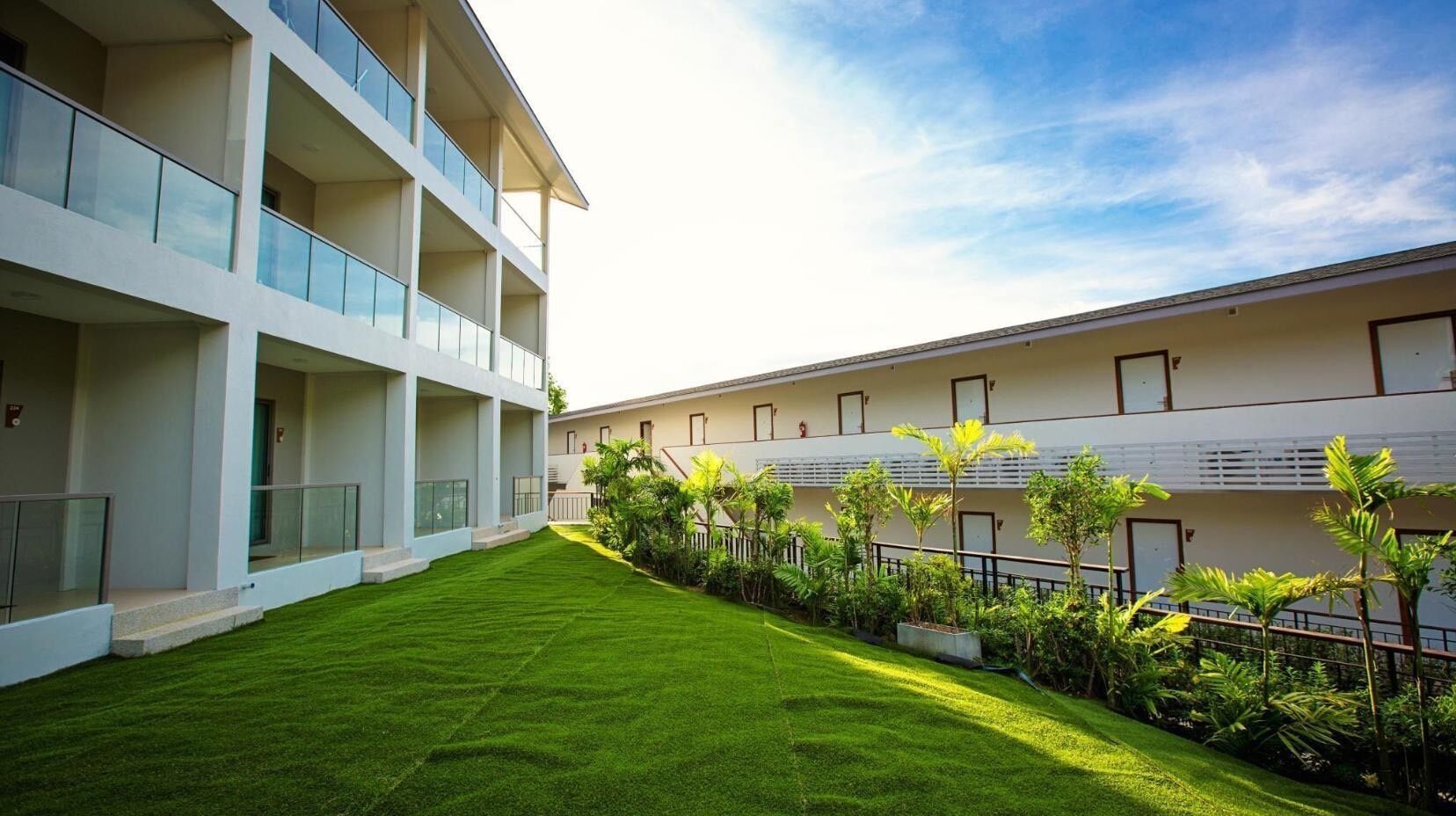 A modern building with multiple balconies and a well-maintained lawn.
