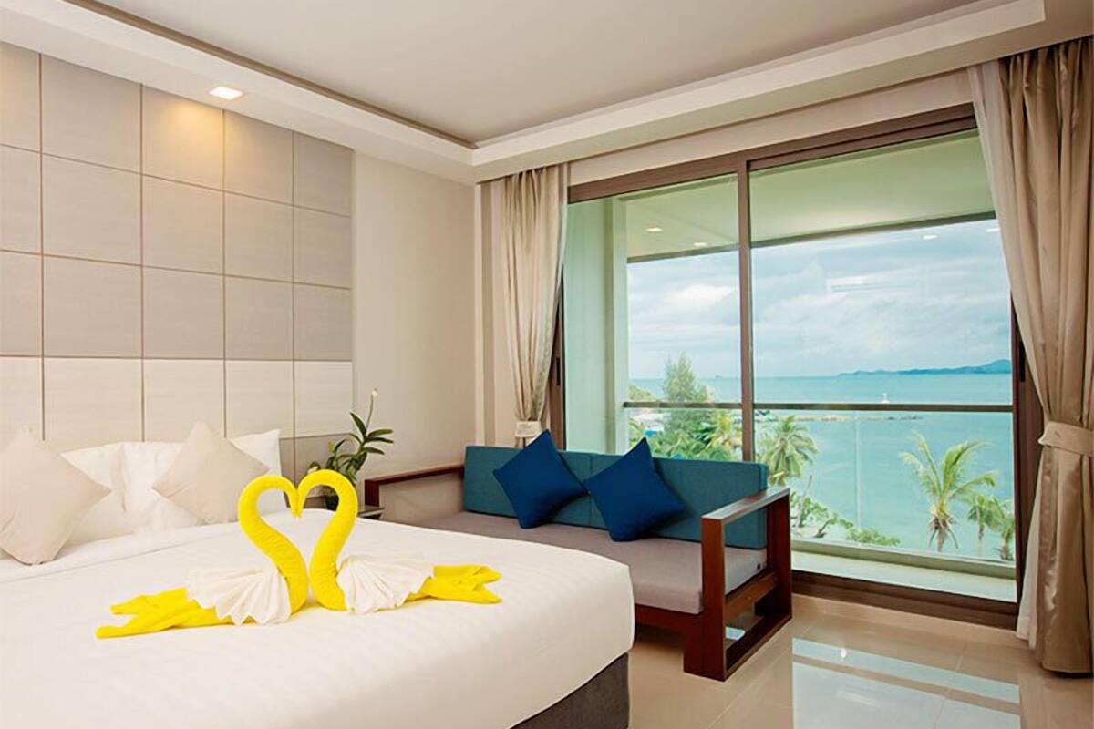 Ein Hotelzimmer mit einem großen Bett, einer Couch und einem Balkon mit Meerblick.