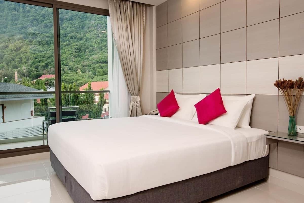 Ein modernes Schlafzimmer mit einem großen Bett, Blick auf eine Berglandschaft und einem Balkon.