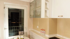 A compact kitchen with a white table, a sink, and a stove. - Bayangol Hotel (Ulaanbaatar)