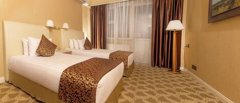 A hotel room with two beds, a large window with sheer curtains, a floor lamp, and a painting on the wall.