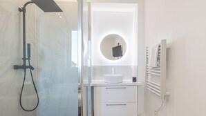 A modern bathroom with a glass-enclosed shower, a white vanity with a round mirror, and a towel rack. - T2 Town Center, Casino (Beausoleil)