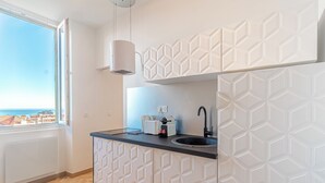 A modern kitchen with a geometric backsplash, a black countertop, and a window with a view of buildings. - T2 Town Center, Casino (Beausoleil)